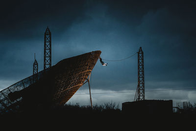 Man climbing a huge satellite dish during blue hour
