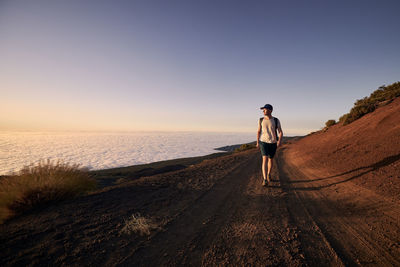 Rear view of man standing on sea against clear sky