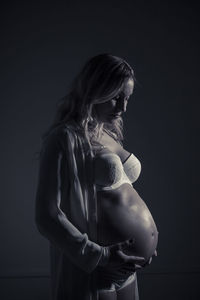 Pregnant woman standing in dark at home