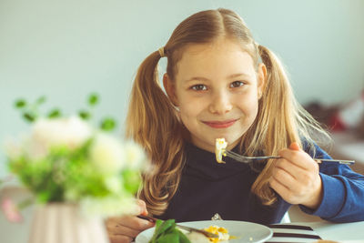 Portrait of smiling girl eating breakfast on at home