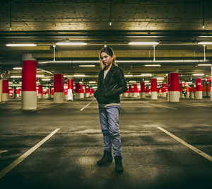 Portrait of girl standing at illuminated parking garage