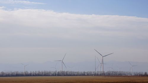 Windmills on field against sky