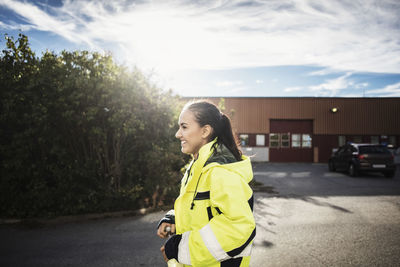 Side view of happy female auto repair student walking outside school