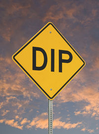 Low angle view of road sign against sky during sunset