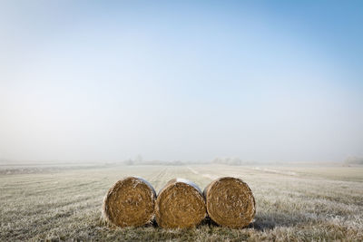 Hay bales on field against clear sky