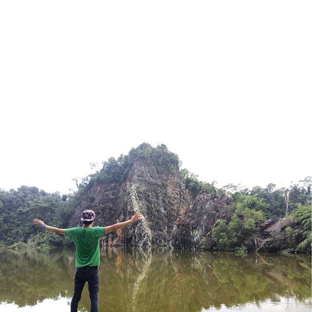 lifestyles, leisure activity, water, standing, clear sky, men, copy space, lake, rear view, three quarter length, casual clothing, nature, reflection, full length, tranquility, holding, day, beauty in nature