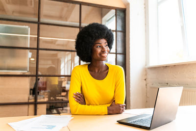 Young woman using mobile phone while sitting on table