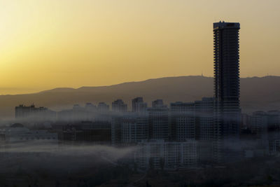 Buildings in city against clear sky during sunset
