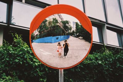 Reflection of man and woman in mirror on road