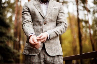 Midsection of well-dressed man standing in park