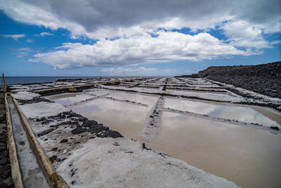 Scenic view of salt pans against blue sky