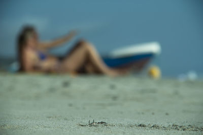 Blurred motion of woman lying on beach against sky