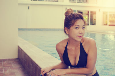 Portrait of woman leaning at poolside