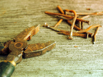 Close-up of old rusty pliers and nails on wooden table