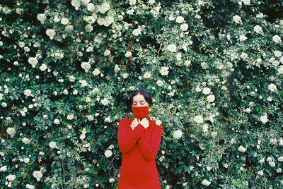 Woman standing by red flowering plants