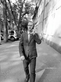 Full length portrait of young man standing on footpath