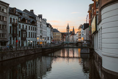 Canal amidst buildings against sky during sunset