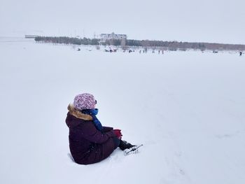 Woman sitting on snow covered land