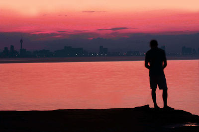 Rear view of silhouette man standing against sky during sunset