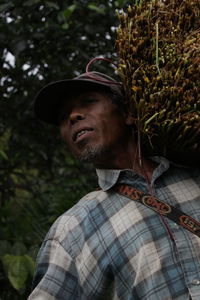 Low angle portrait of farmer carrying crop on shoulder