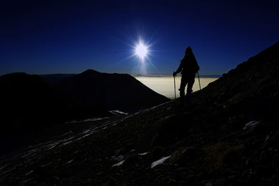 Silhouette hiker standing on mountain against sky