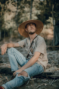 Portrait of man wearing hat sitting on land