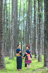 Couple hmongs holding hands and walking in the pine wood, man and woman in hmong clothes