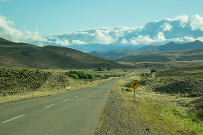 Road leading towards mountains against sky