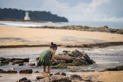 Full length of man on rock at beach against sky