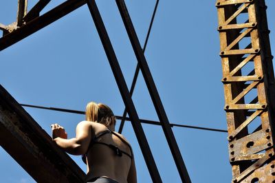 Low angle view of woman climbing on bridge