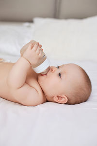 Portrait of shirtless baby boy lying on bed at home