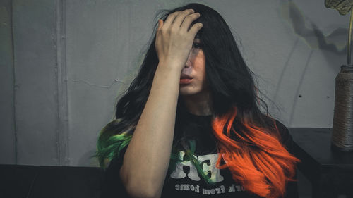 Portrait of young woman against wall