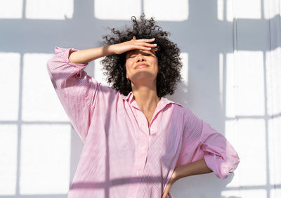 Woman shielding eyes standing in front of wall