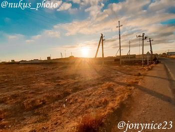 Road sign on field against sky during sunset