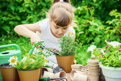 Side view of young woman picking potted plants