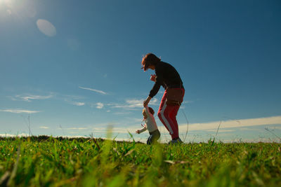 Mother and daughter on grass against sky