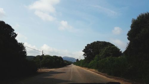 Road amidst trees against sky