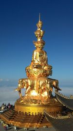 Gold buddha temple against blue sky