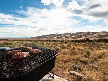Bbq hamburgers on a grill at scenic location with sand dunes in colorado