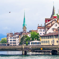 Arch bridge over river against buildings in city