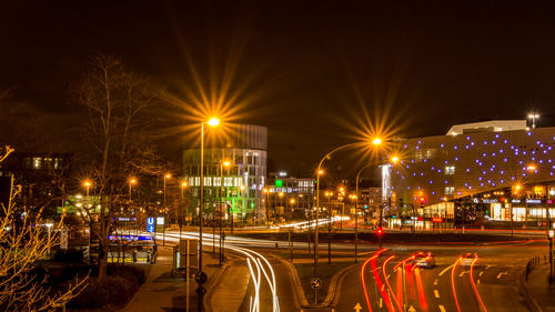 Light trails on road in city against sky at night