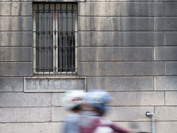 Blurred motion of couple riding motorcycle against building