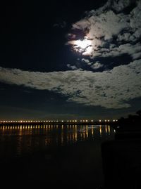 Silhouette wooden posts in lake against sky at night