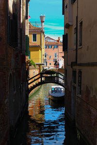 Boats moored in canal amidst city against sky