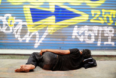 Homeless man sleeping outside shop