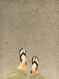 Low section of man wearing flip-flops while standing on street