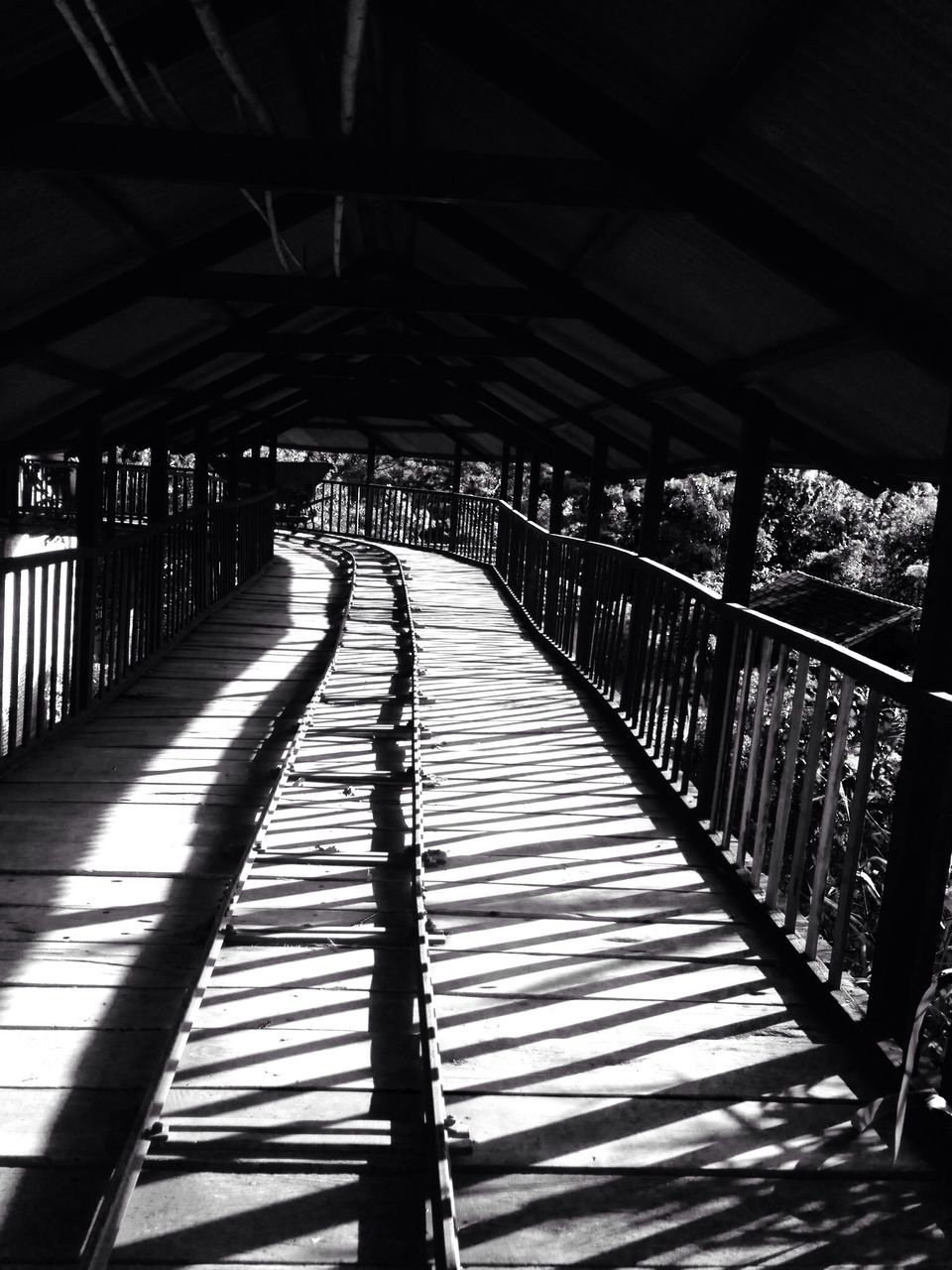 the way forward, railing, diminishing perspective, vanishing point, indoors, footbridge, shadow, built structure, sunlight, walkway, in a row, long, incidental people, architecture, narrow, bridge - man made structure, wood - material, boardwalk, empty, transportation