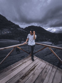 Full length of man standing on railing against mountain