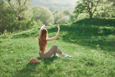 Rear view of woman sitting on grassy field