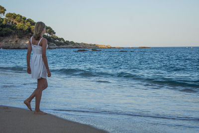 Woman standing on beach against clear sky